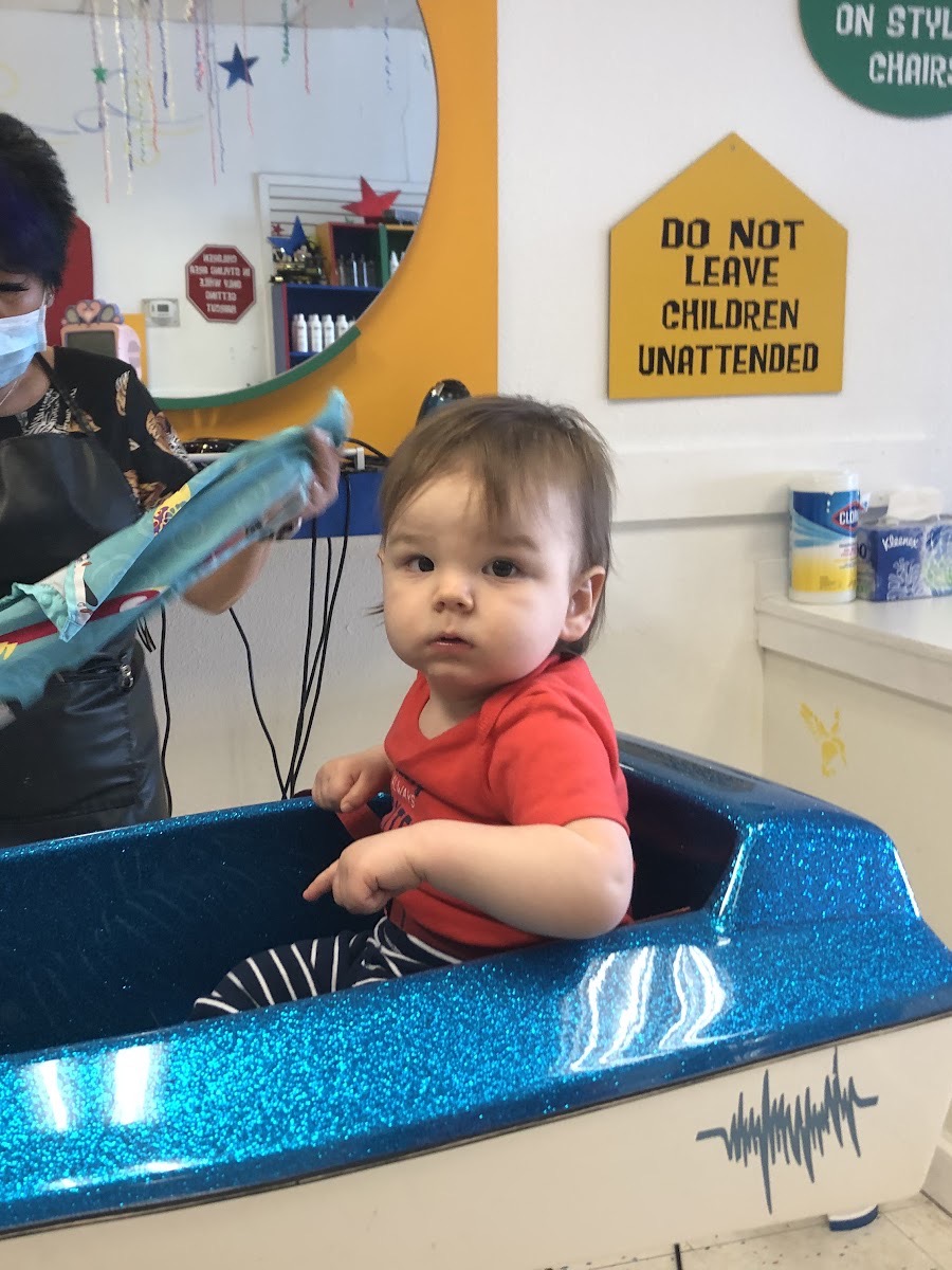 A baby in the sparkly blue race car chair