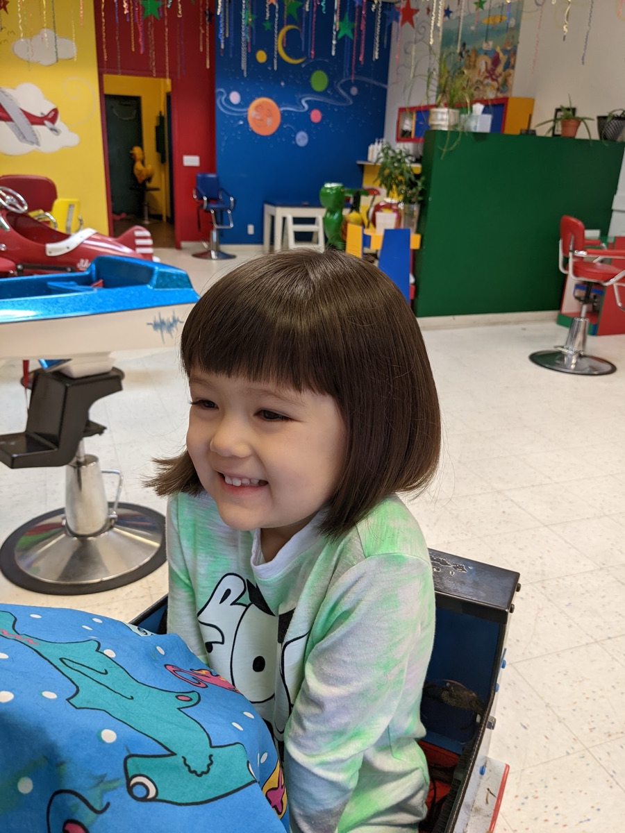 A smiling girl with a new bob and bangs